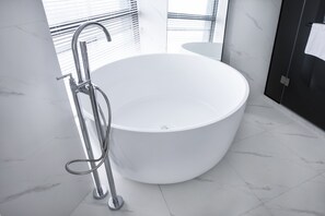 Un baño moderno con una bañera independiente, cabina de ducha de vidrio y suelo de mármol blanco.
