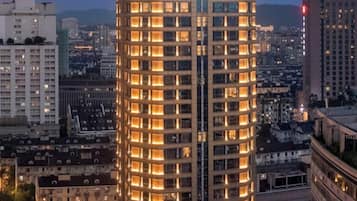 A tall, cylindrical hotel with multiple floors and illuminated windows, surrounded by other buildings.