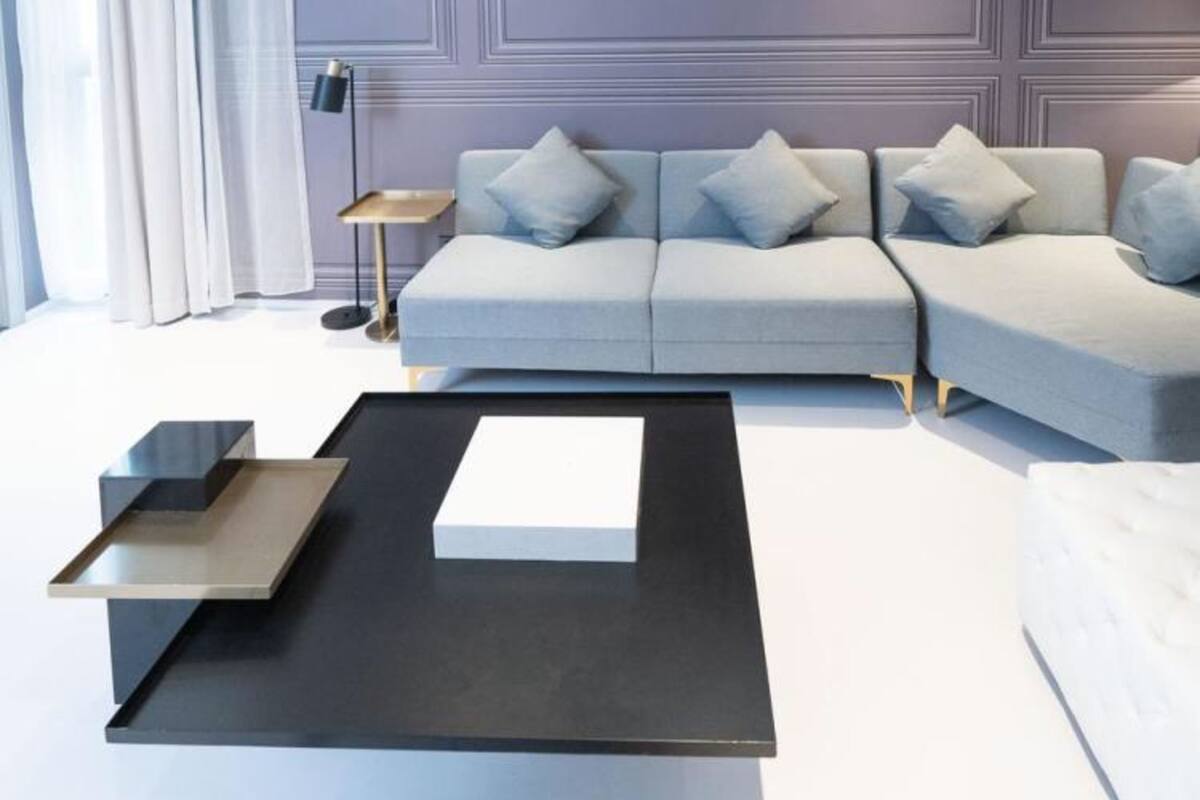 Una sala moderna con un sofá gris, una mesa de centro negra y una mesita auxiliar pequeña.