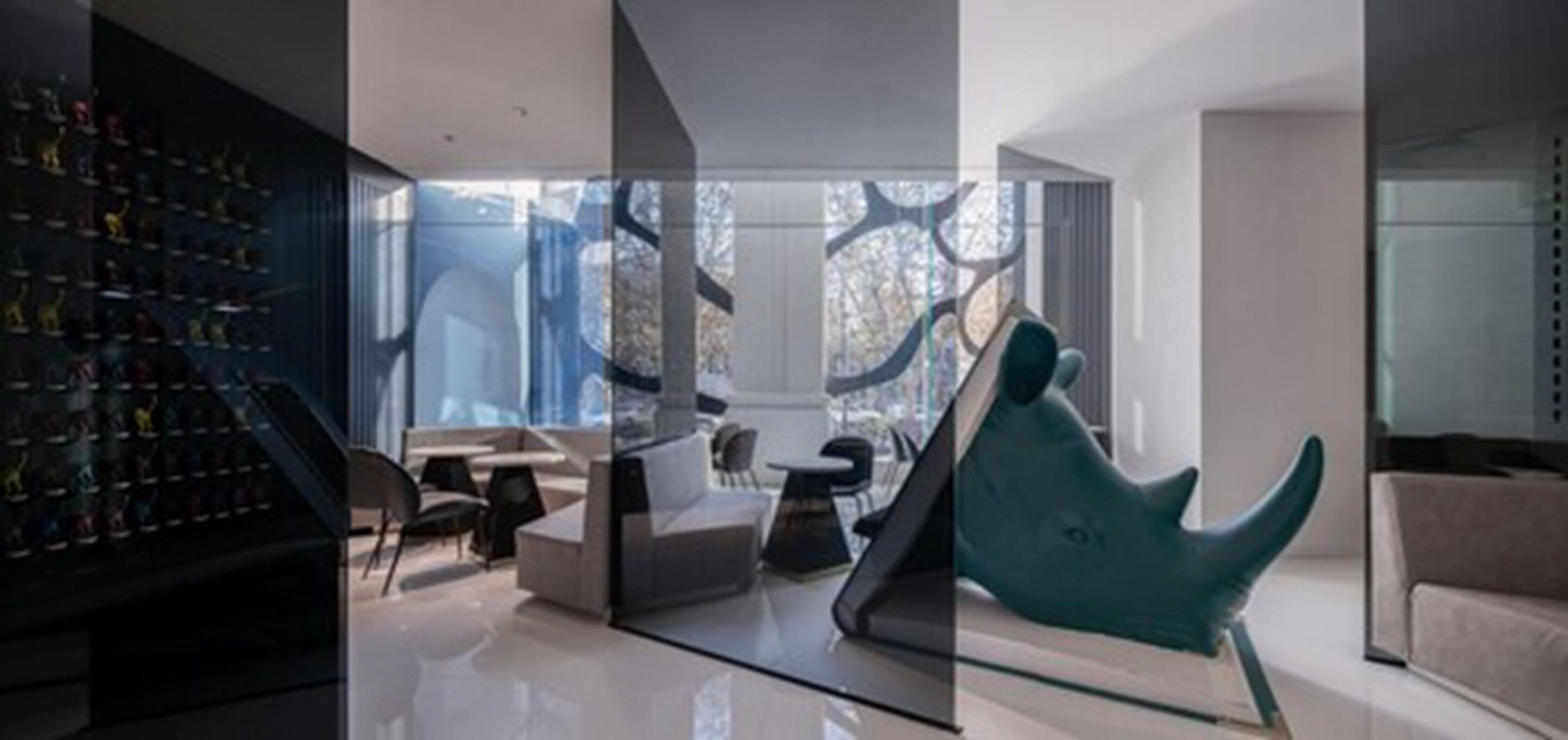 Een modern interieur met een glazen scheidingswand, een verzameling schoenen links, een blauwgroene stoel en een bank.