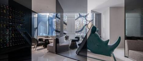 Ein modernes Interieur mit einer Glastrennwand, einer Schuhsammlung links, einem türkisfarbenen Sessel und einem Sofa.
