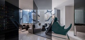 Ein modernes Interieur mit einer Glastrennwand, einer Schuhsammlung links, einem türkisfarbenen Sessel und einem Sofa.