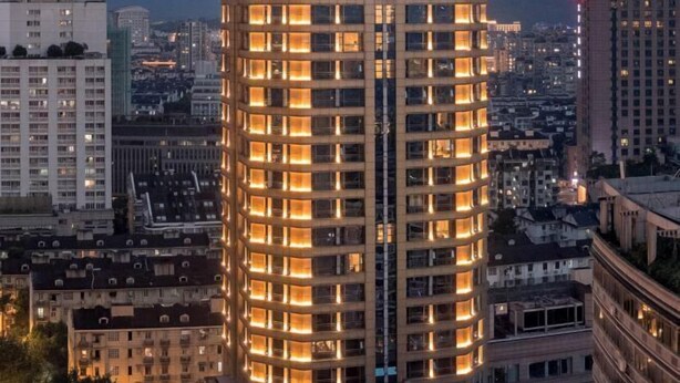 Un edificio alto con varios pisos, que presenta una cuadrícula de ventanas y una estructura vertical central.