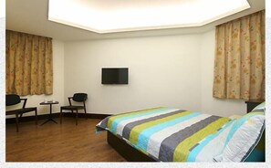 A hotel room with a bed, a desk, a chair, and a TV on the wall. - Lotus B&B (Hualien City)
