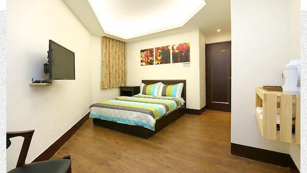 A bedroom with a bed, a flat-screen TV, a wooden desk, and a small cabinet. - Lotus B&B (Hualien City)