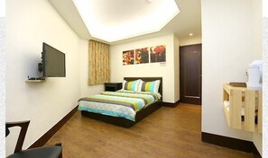 A bedroom with a bed, a flat-screen TV, a wooden desk, and a small cabinet. - Lotus B&B (Hualien City)