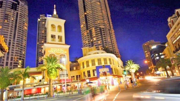 A hotel with a prominent tower, a curved facade, and palm trees in front.