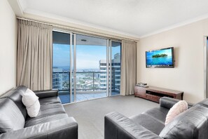A modern living room with a large sliding glass door leading to a balcony with a city view.