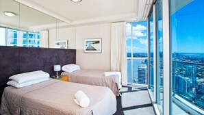 A hotel room with two beds, a large window with a city view, a mirror, and a framed picture on the wall. - The Towers Chevron Renaissance Holidays Gold Coast (Surfers Paradise)
