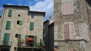 A stone building with green shutters and a sign indicating a place for rent. - Quiet holiday home in Les Vans with pool (Les Vans)