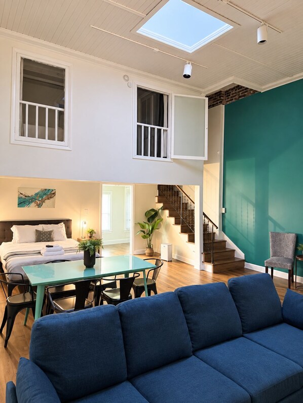 A spacious living area with a sofa, a dining table, and a staircase leading to an upper level. - Steps from Broadway - The Lofts @ 107 - Unit 2, Steps from Broadway - The Lofts @ 107 - Unit 2 (Nashville)