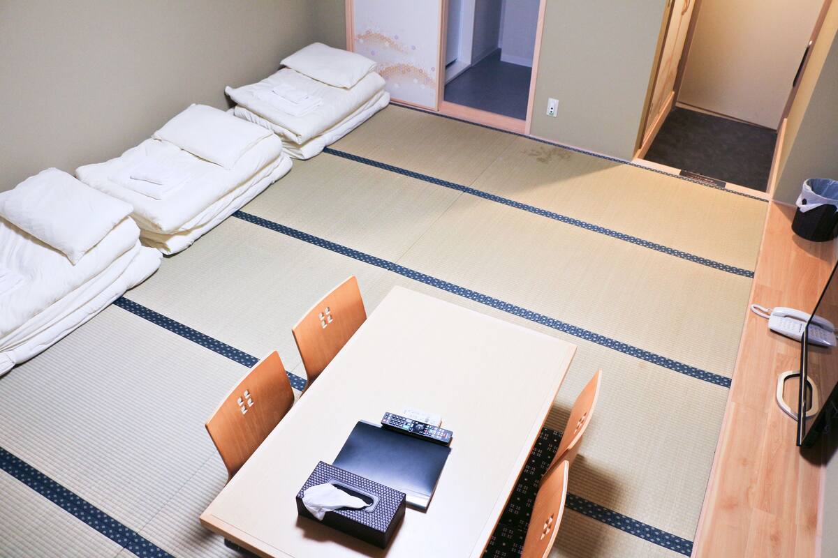 A traditional Japanese room with tatami flooring, a low table with a black mat, and a wooden chair.
