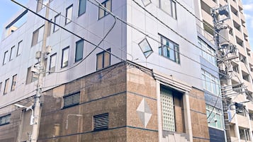 Un edificio de varios pisos con un diseño arquitectónico moderno, que combina fachadas de vidrio y ladrillo, y una entrada a nivel de calle con un carril bici rojo.