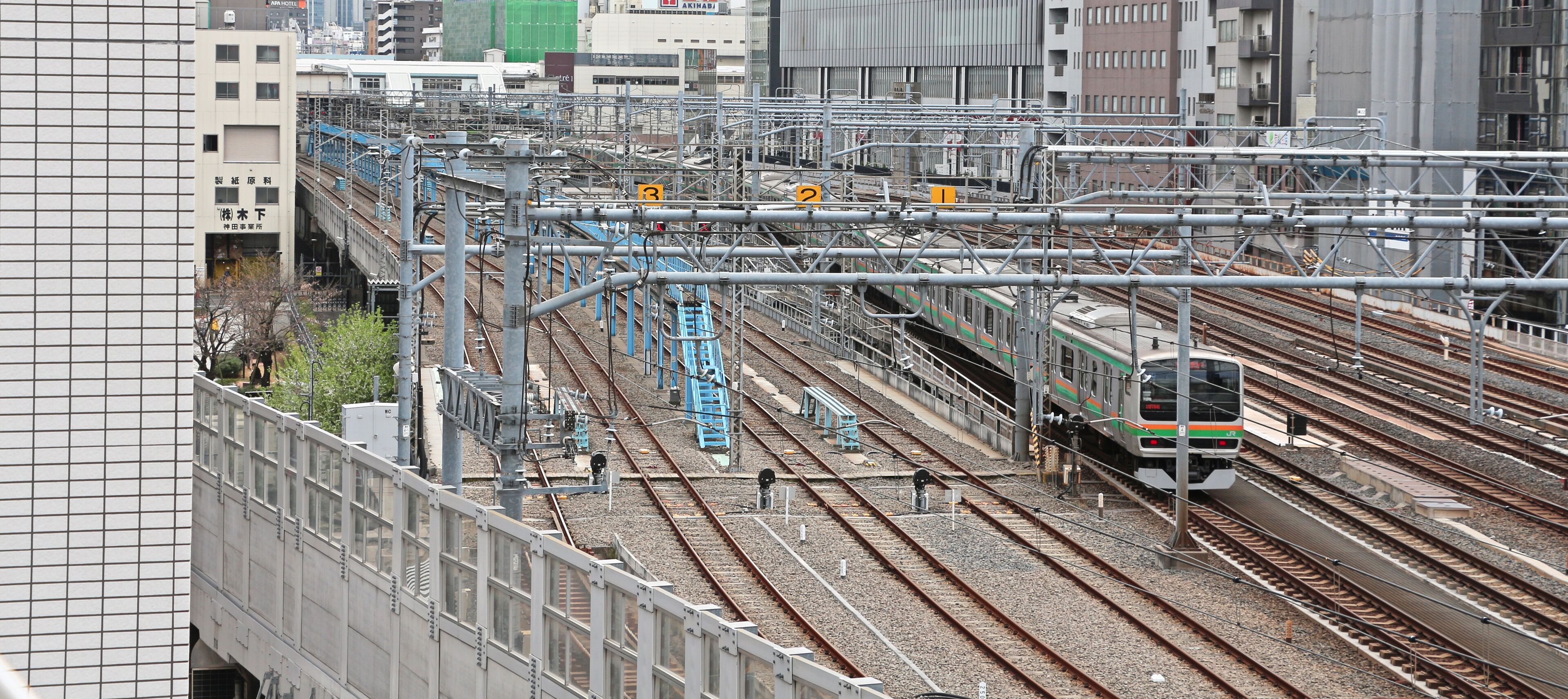 Una estación ferroviaria concurrida, con múltiples vías y líneas aéreas, rodeada de edificios urbanos.