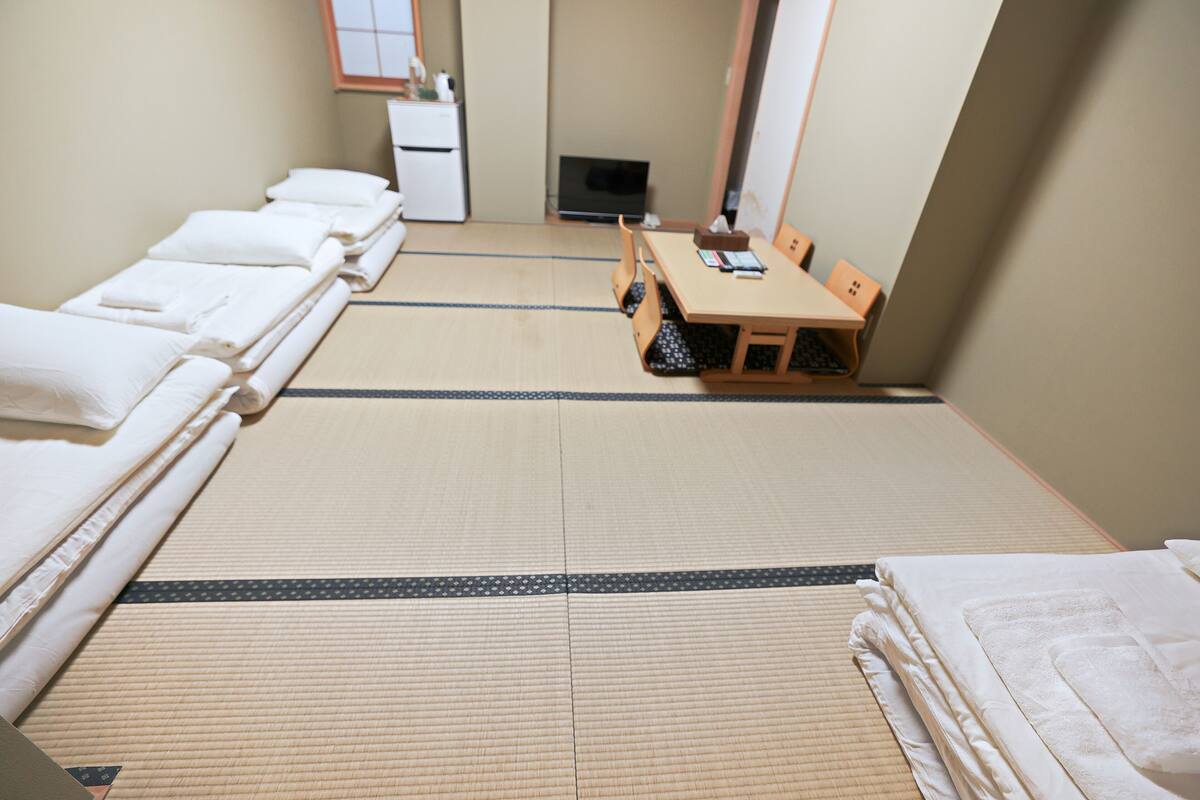 A tatami mat room with a bed, a desk, and a small cabinet.