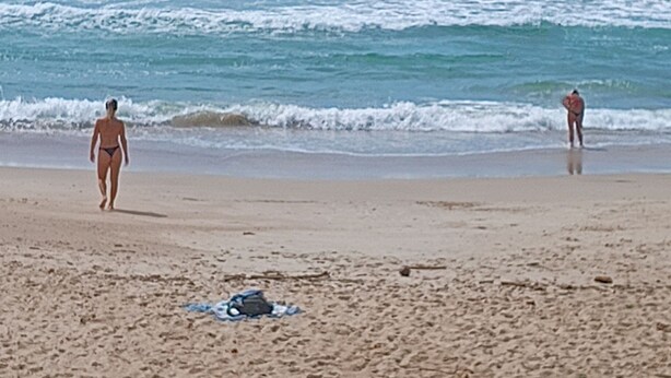 A beach with people walking and swimming in the water. - Studio Morro das Pedras (Florianópolis)
