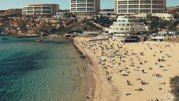 Ein Küstenhotel mit mehreren Gebäuden, einem Sandstrand und klarem, blauem Wasser.