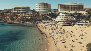 Un hôtel situé sur la côte, composé de plusieurs bâtiments, avec une plage de sable fin et une eau cristalline.