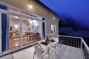 A modern house with a balcony, sliding glass doors leading to a living room, and a dining area with a table and chairs. - Larisa Resort, Mussoorie (Dehradun)