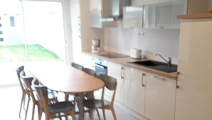 Una cocina moderna con una mesa de comedor y sillas, armarios blancos y un ventanal grande.