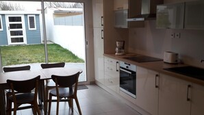 Una cocina moderna con comedor, ventanas amplias y vista a una casa.