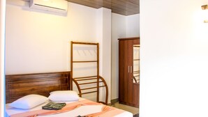 Ein Hotelzimmer mit einem Bett, einem hölzernen Kopfteil, einem Kleiderschrank und einer Klimaanlage.