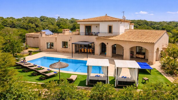 Eine Villa mit Swimmingpool, Sitzgelegenheiten im Freien und einem Garten.