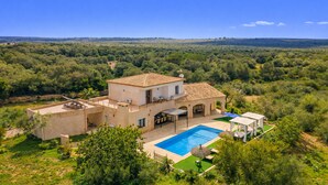 Eine Villa mit Swimmingpool, Sitzgelegenheiten im Freien und Blick auf die umliegende Landschaft.