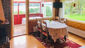 Een gezellige kamer met een houten tafel en stoelen, een open haard en een televisie.