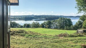 Uitzicht vanuit een raam op een meer, met een grasveld en bomen op de voorgrond.