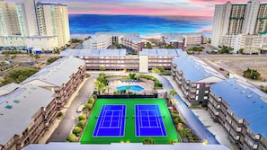 Ein Hotelkomplex mit mehreren Gebäuden, einem Tennisplatz und einem Poolbereich.