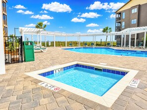 A swimming pool with a white deck, a separate shallow area, and a no diving sign.