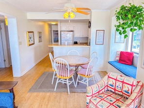 A compact living space with a dining area, a kitchenette, a ceiling fan, and a window seat.