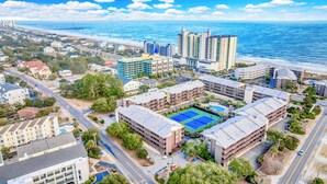 An aerial view of a coastal hotel complex with multiple buildings, a tennis court, and a beach in the background. - Experience Tilghman Beach and Racquet Club Unit 208! Oceanfront, Pools, Tennis, Close to Main Street! (North Myrtle Beach)