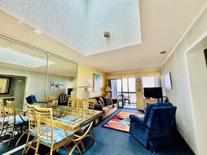 A living room with a glass dining table, sofas, and a television.