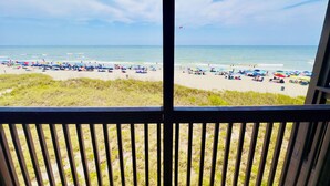 A beach view from a window with a view of the ocean and beachgoers. - Experience Tilghman Beach and Racquet Club Unit 304! Oceanfront, Pools, Tennis, Close to Main Street! (North Myrtle Beach)