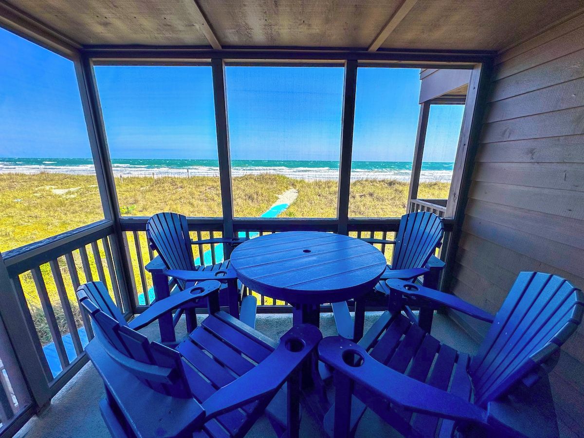 A covered outdoor seating area with a view of the beach.