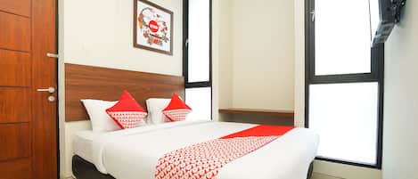 Hotelkamer met een groot bed, een houten hoofdbord, een ingelijst kunstwerk aan de muur en een raam met uitzicht.