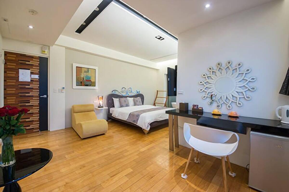 Una habitación de hotel moderna con una cama, un escritorio, una silla y una kitchenette.