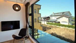 Een moderne kamer met een groot raam, een flatscreen-tv aan de muur en een zwarte stoel.
