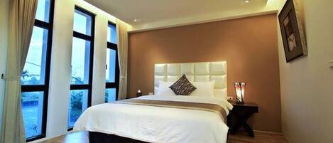 A modern bedroom with a large bed, a headboard, and a nightstand with a lamp.