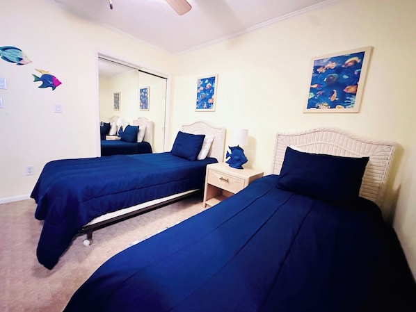A room with two beds, a nightstand, and a mirror.