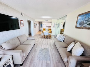 Relax in this open-plan living area featuring a flat-screen TV, comfortable sofas, and a dining table.