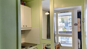 A compact kitchen with white cabinets, a sink, and a stove. There is a dining area with a table and chairs.