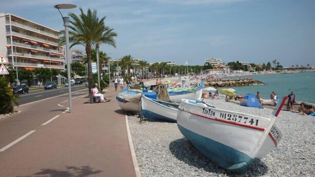 A beachside scene with boats, a pedestrian path, and a building in the background. - F2 ON THE GROUND FLOOR 150m from the beaches and shops / 5pers / 48m2 (Cagnes-Sur-Mer)