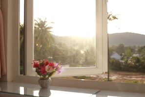 Ein Fenster mit Landschaftsblick, eine Vase mit Blumen und ein Spiegelbild im Glas.