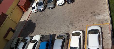 A parking lot with multiple cars parked in rows, adjacent to a building with a yellow facade and a red door.