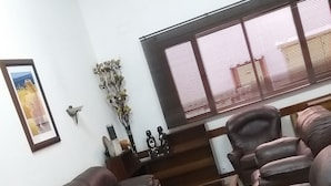 Uma sala de estar com vários sofás de couro, uma mesa de centro de vidro e um quadro pendurado na parede.