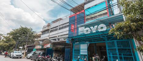 A commercial building with multiple parked motorcycles and cars on the street.