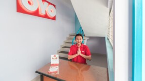 A hotel reception desk with a large 'OYO' sign, a staircase, and a number '1' on the wall. - Hotel O Balcon Biru (Jakarta)